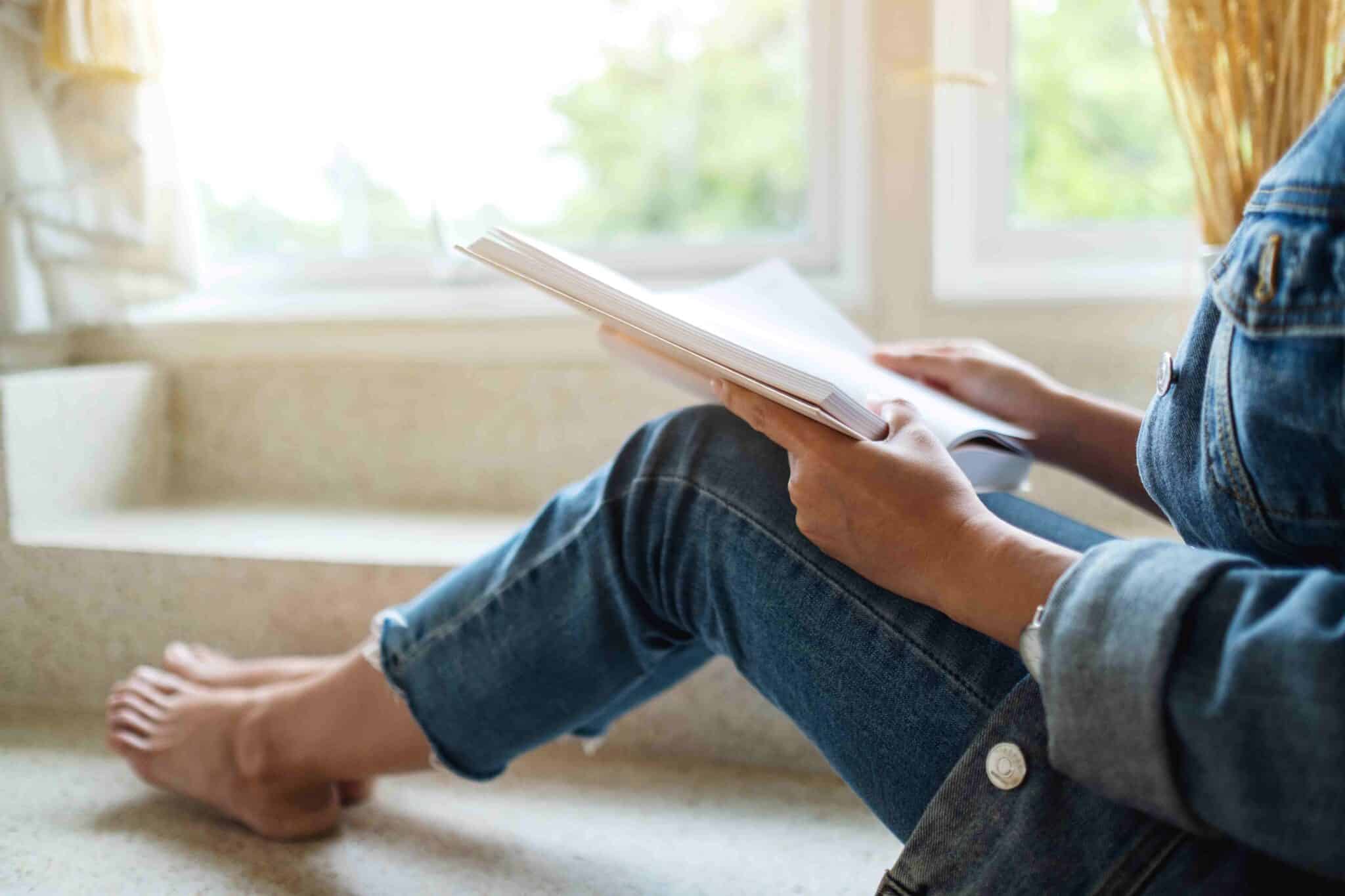 Adult Reads a Book Near a Window
